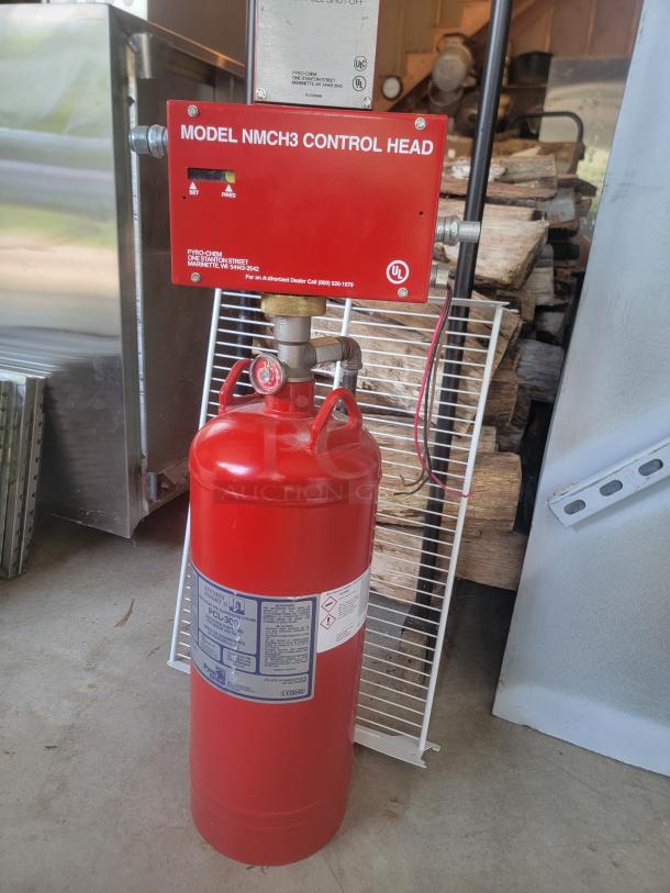 Red Pyro-Chem fire suppression system with Model NMCH3 Control Head. Labels indicate safety instructions and usage.