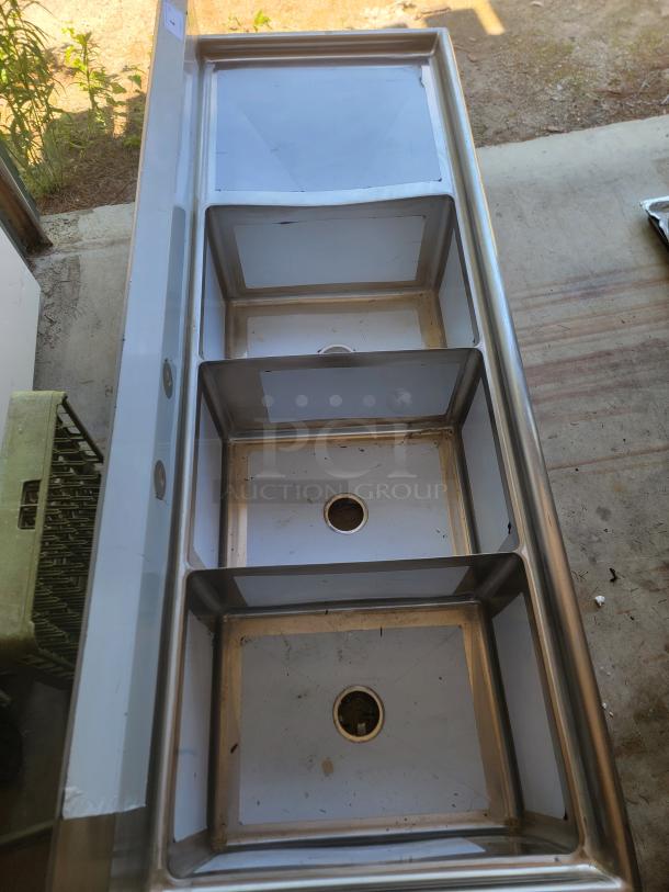 Stainless steel triple compartment sink, used condition, visible drainage holes, suitable for commercial kitchen use.