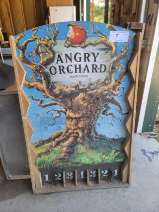 Angry Orchard promotional sign featuring a twisted tree design, numbered slots at the bottom, and a label marked "7 QTY."