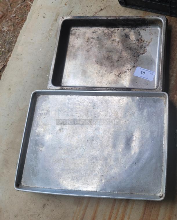 Two metal baking trays; one with rust and a label marked "10 QTY." Used condition, showing wear and discoloration.