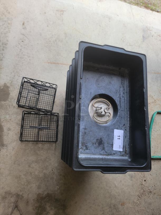 Stack of black plastic bins with wire baskets and metal drain plug, item tag marked "71."