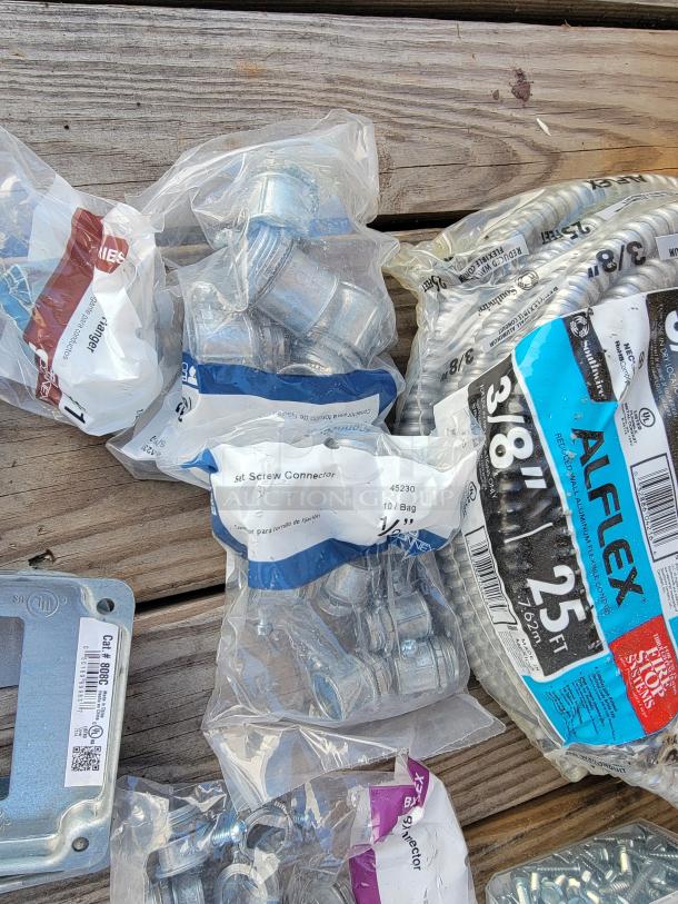 Electrical supplies assortment including 3/8" Alflex 25 ft conduit, set screw connectors, and metal outlet box cover, new in packaging.