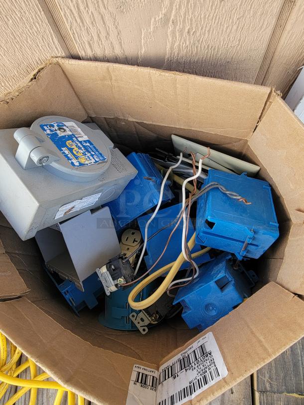 Box of assorted electrical supplies including blue junction boxes, wires, and a circuit breaker. Ideal for wiring projects.