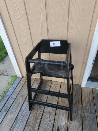 Two sturdy wooden restaurant high chairs by Lancaster Table and Seating, one shown outside, black finish, durable and easy to clean.