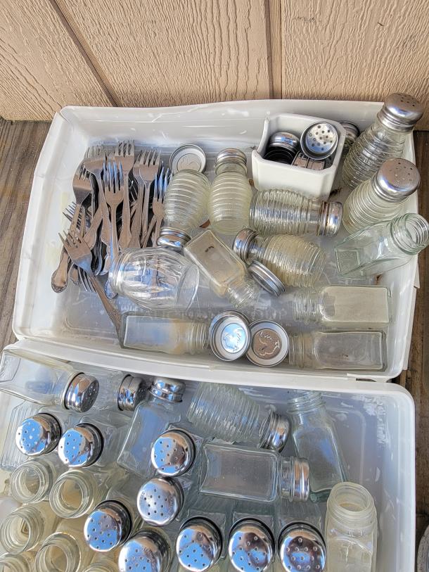 Assortment of kitchenware with various spice jars, shakers, and forks. Items in used condition, ideal for kitchen organization.