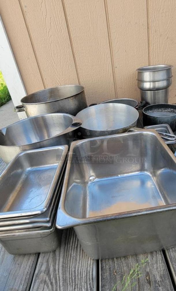 Assorted stainless steel and aluminum cookware and utensils, ideal for commercial kitchens. Includes pots, pans, and trays.