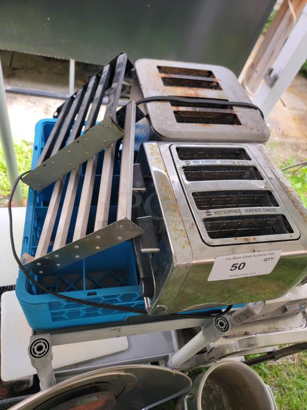 Assorted commercial kitchen lot with two metal toasters, trays, and cooking pots. Visible rust on toasters. Auction label "50 QTY."