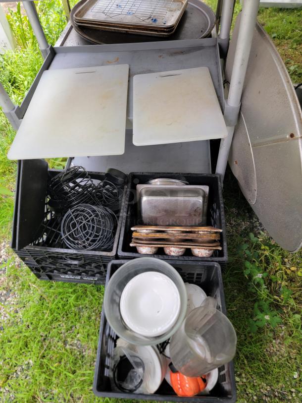Assorted commercial kitchen lot with cutting boards, baking trays, dishes, and pots, indicating moderate wear.