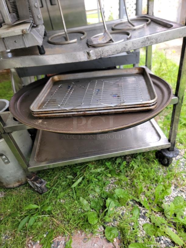 Assorted commercial kitchen items on metal cart; includes trays, cooking pots, and more. Used condition. Ideal for bulk purchase.