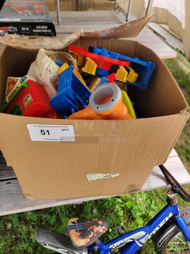 Box of children's outdoor toys with colorful pieces and worn children's bicycle, visible auction label "51 QTY".