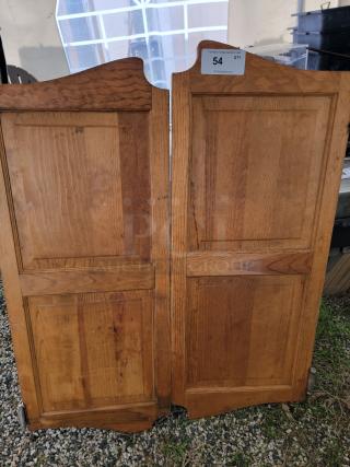 Vintage wood saloon doors with natural finish, featuring panel design. Condition shows rustic wear, auction tag "54" visible.