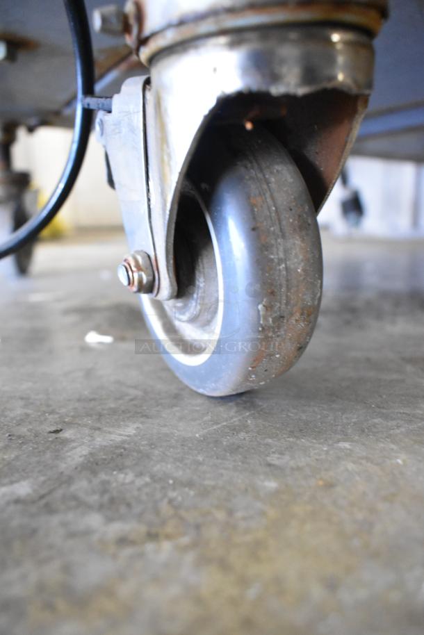 Close-up of a caster wheel on a Hobart MG2032 commercial meat mixer grinder, showing rust and wear.