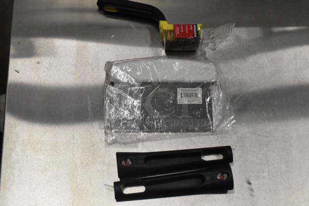 Stainless steel countertop with cleaning tools, including a scraper and brush, packaged in plastic.