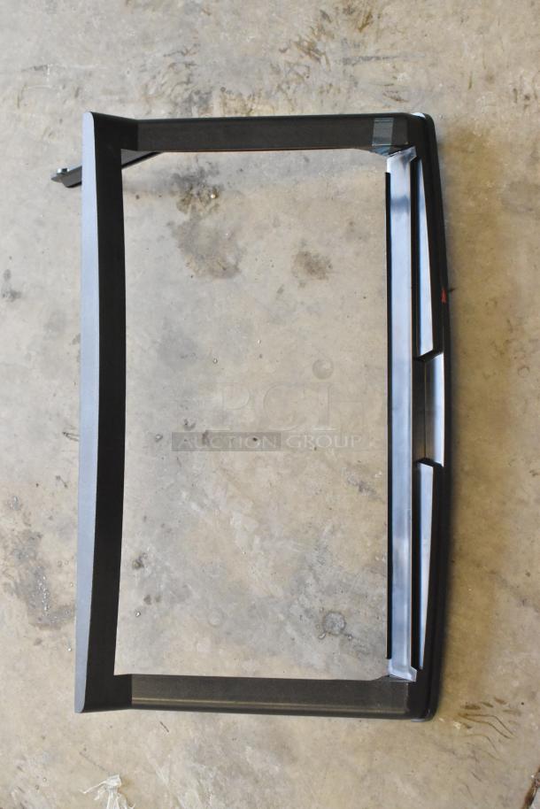 Black rectangular frame part on a concrete floor, related to a commercial ice machine. No visible markings.