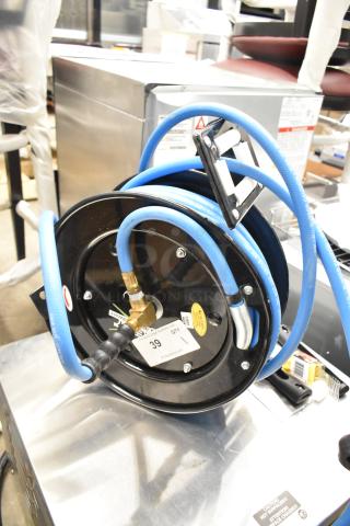 Brand new Regency hose reel, black with blue hose, scratch and dent condition, tags showing model and auction details visible.