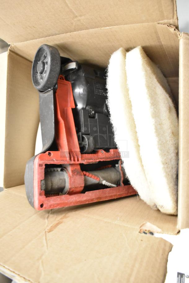 Box containing a vacuum head, two round cleaning pads, and dispenser. Items appear used, showing moderate wear.