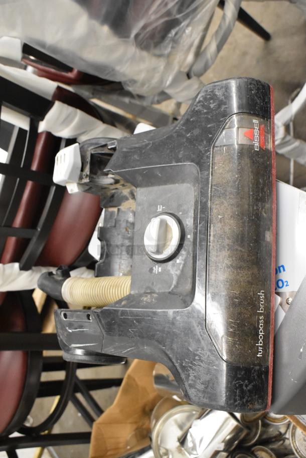 Lot including Bissell vacuum head with turbobrush label, round cleaning pad, and dispenser. Used condition, visible wear.