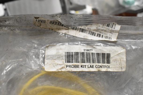 Plastic bag labeled "Probe Kit LAE Control" with barcode 218877. Bag appears worn and contains yellow components.