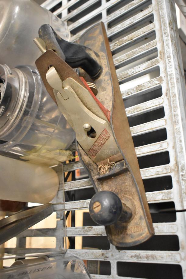 Stanley Handyman plane on metal shelf, shows wear, black handle, rust visible, label reads "Stanley Handyman".