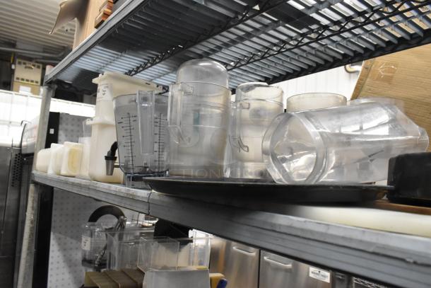 Lot of clear poly pitchers, bins, and dispenser on metal shelving, showing measurement markings and varied sizes, in used condition.