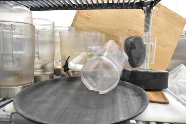 Lot of clear poly pitchers, bins, and dispenser on a metal shelf; lightly used with visible wear signs.