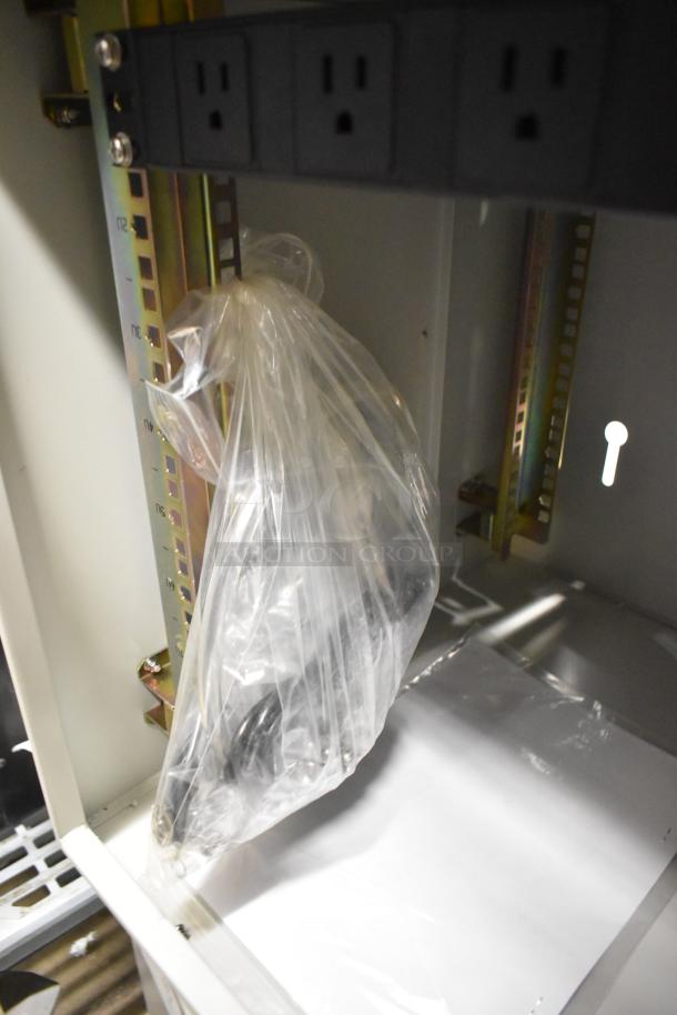 BlackShields DC0300 white metal cabinet interior, showing power outlets and accessories in a plastic bag.