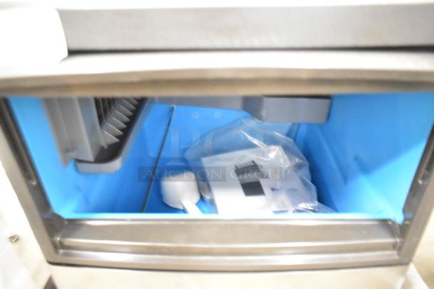 Brand new Manitowoc UDP0065A-161 undercounter ice machine; 31 lb. bin, 62 lb. capacity; 115 volts, 1 phase; visible scoop and manual.