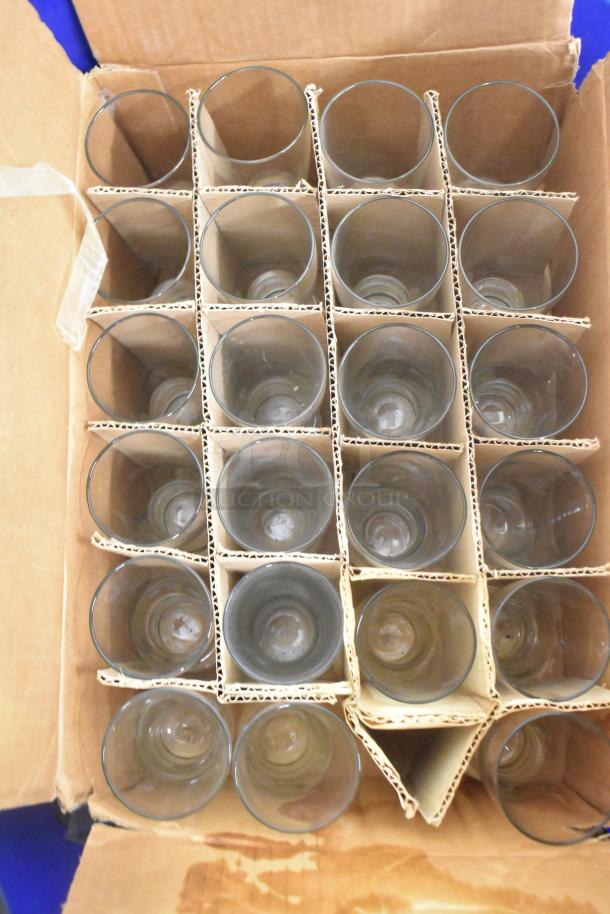 Box of 24 glass tumblers in cardboard dividers, shown from top view. Part of Boltic SHAG-K07F lot including various items.