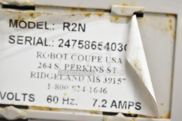 Robot Coupe R2N food processor base label showing model, serial number, voltage, and manufacturer info. Slight wear visible.