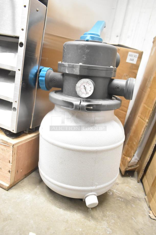 Gray industrial tank with attached gauge and blue handle, used condition. Features multiple inlets and labeled controls.