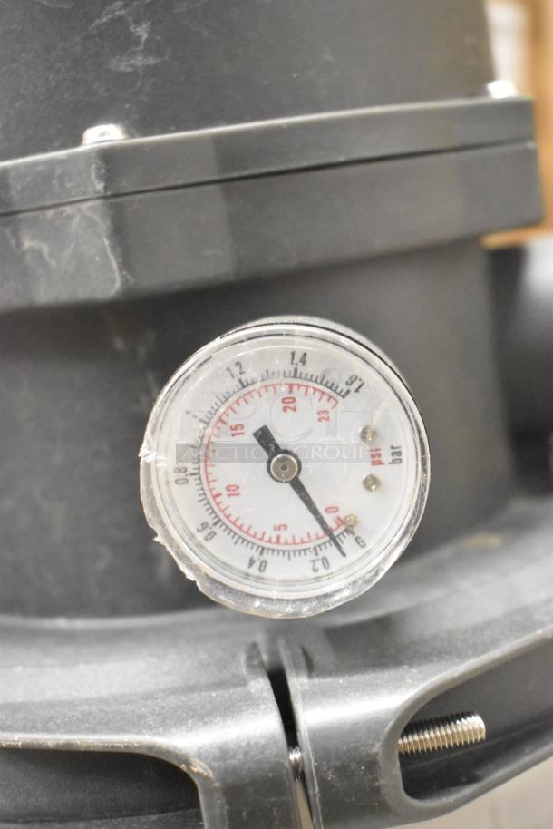 Black tank with pressure gauge displaying PSI and bar measurements, moderate wear visible on surface.