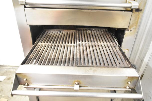 Garland stainless steel commercial gas vertical upright broiler, slightly worn, with visible grate and handle, designed for efficient cooking.