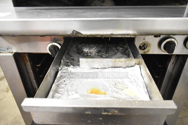 Garland stainless steel commercial gas-powered vertical upright broiler, visible wear, features control knobs and drip tray.