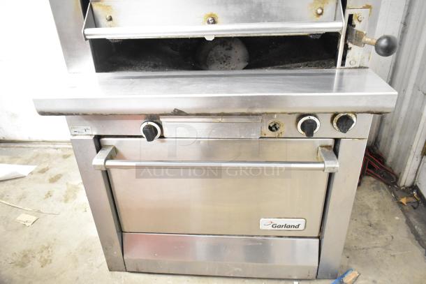 Garland stainless steel gas-powered vertical upright broiler, commercial-grade, shows signs of use, visible brand label.