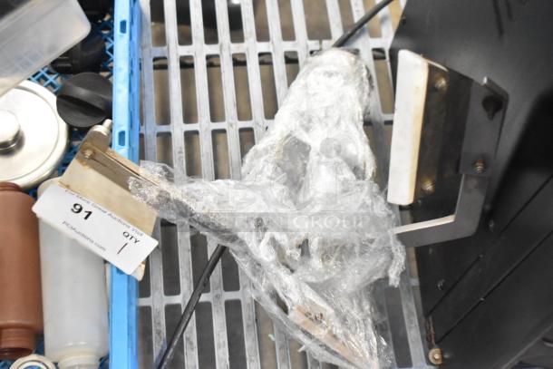 Metal auger wrapped in plastic on a metal shelf. Auction tag with "91" visible, indicating item number.