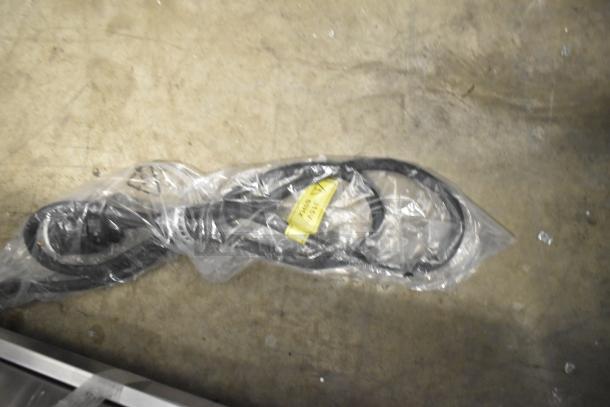 Plastic-wrapped electrical cord on the floor, part of the ServIt 423HDM26SA display case, showing power specifications.