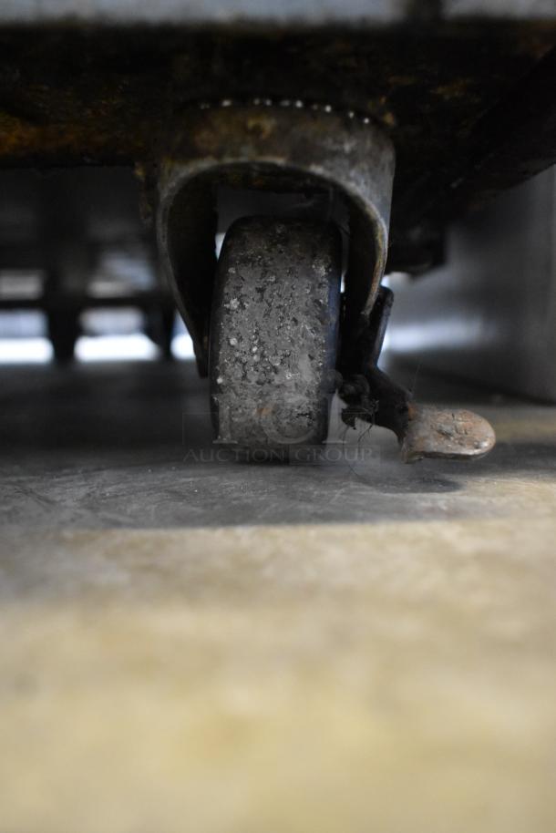 Close-up of a worn caster wheel under the Beverage Air UCR48A commercial cooler. Visible signs of rust and use.