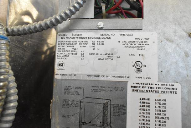 Manitowoc SD0602A commercial ice head on ice bin, 208-230V, 1 phase, includes labels detailing specs and model information.