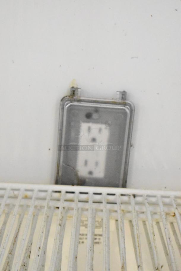 Interior of True GDM-49 cooler, showing poly-coated rack and electrical outlet. Visible wear, suitable for commercial use.