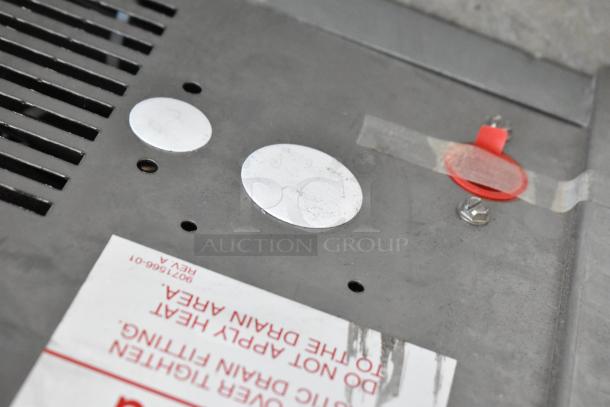 Close-up of a gray panel from the Ice-O-Matic ICEU220FA5 ice machine, showing vents and warning labels.