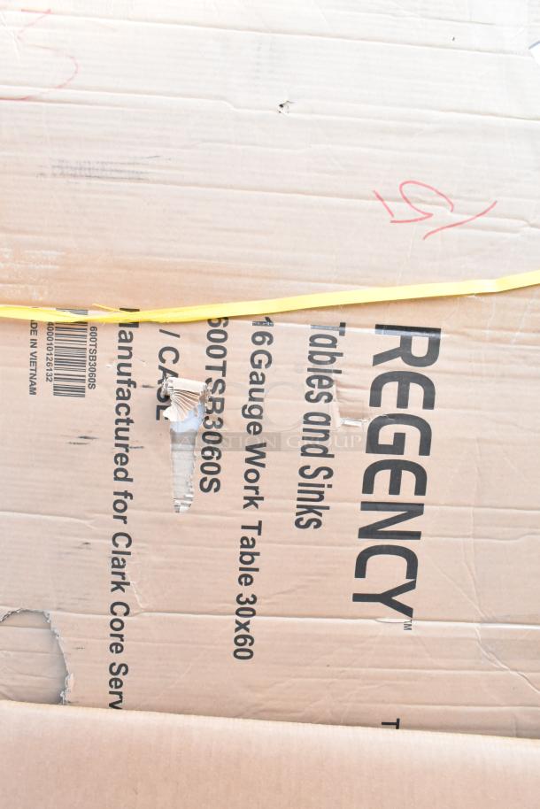 Cardboard box labeled "Regency Tables and Sinks," showing minor damage. Contains 16 gauge work table 30x60. Part of auction lot.