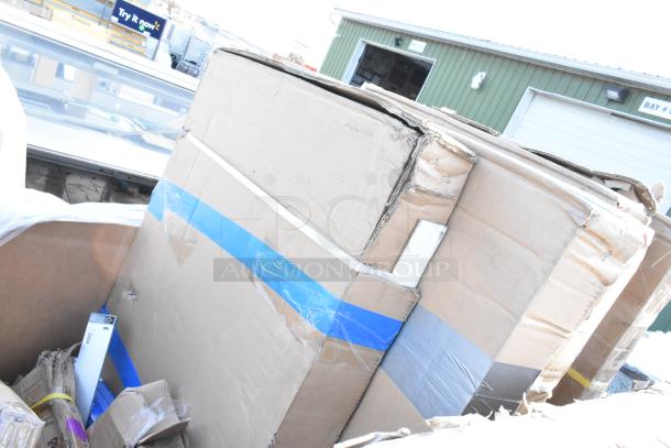 Cardboard boxes with visible wear, containing assorted scratch and dent items including a blue chair, sinks, and pan racks.