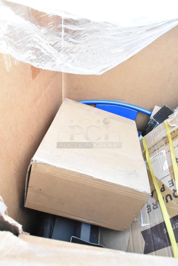 Cardboard box with mixed scratch and dent items including a blue chair partially visible. Items are in new condition.