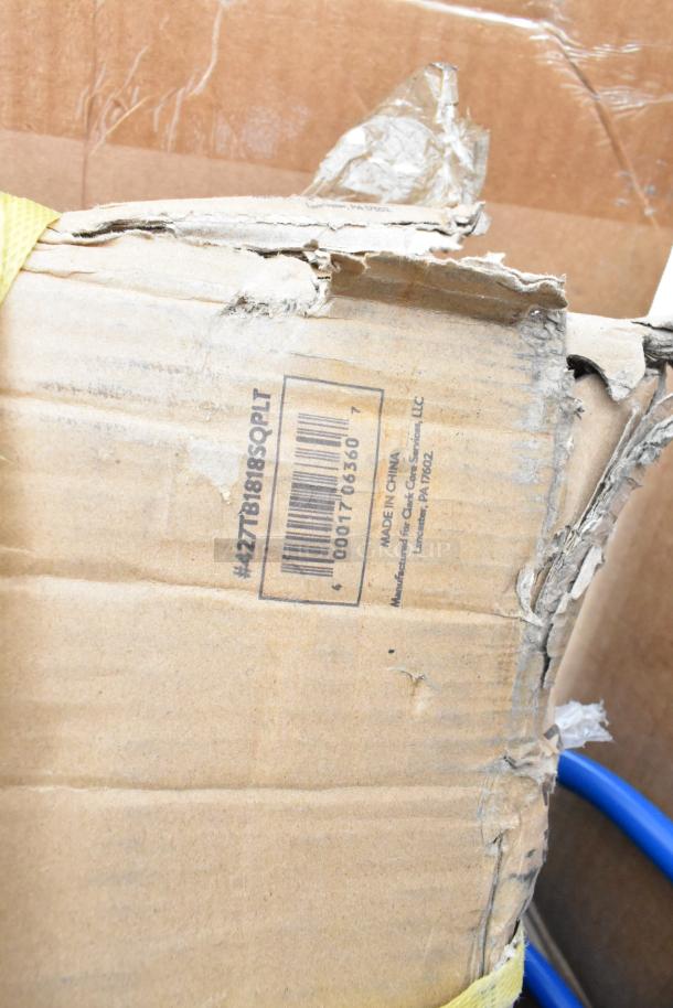 Damaged cardboard box with visible barcode and label; partially obscures a blue chair, part of auction lot including sinks and pan racks.