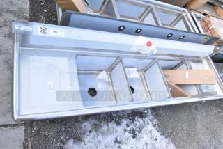 Steelton stainless steel 3-bay sink with dual drain boards. Scratch and dent condition, tags visible, model 522CS31818LR.
