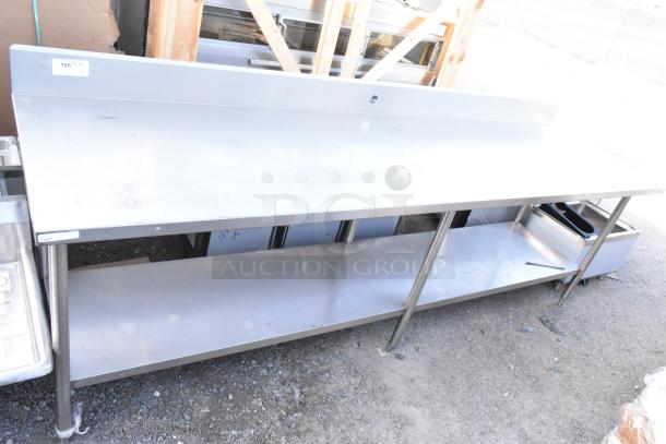 Winholt stainless steel table with under shelf and backsplash, durable condition, features storage space and a clean surface.