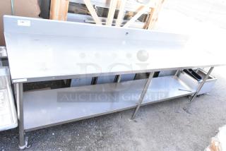Winholt stainless steel table with under shelf and backsplash, durable condition, features storage space and a clean surface.