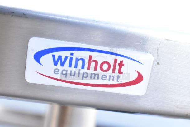 Winholt stainless steel table with undershelf and backsplash, visible branded label “Winholt Equipment.”