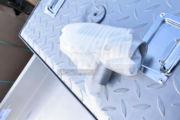 Stainless steel grease trap with diamond plate cover, new condition, foam-wrapped pipe fitting visible for protection.