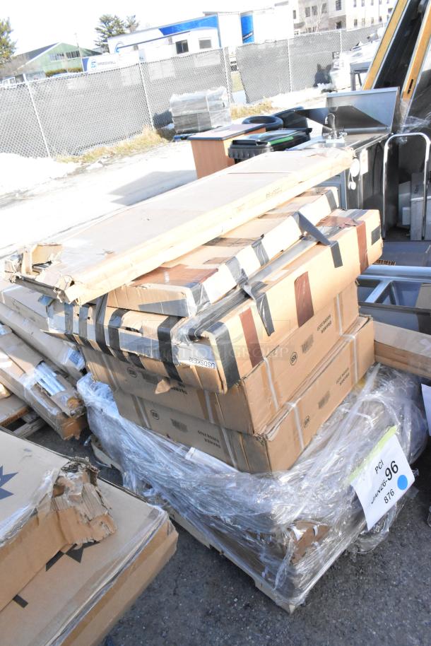 Boxes of new scratch and dent items including table base columns and drawer, stacked outdoors, some packaging damaged.